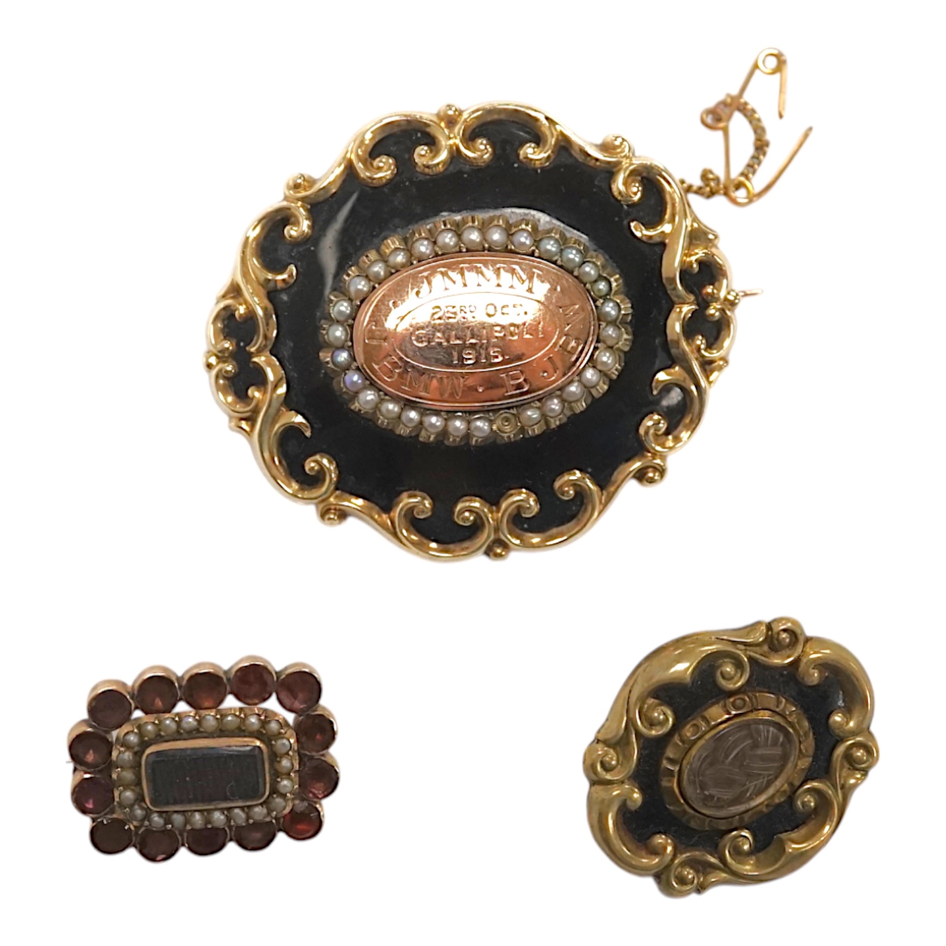 Three assorted late 19th/early 20th century yellow metal mounted mourning brooches, including black enamel and split pearl inscribed 'JMMM. BJBW. JBMW. 23rd Oct Gallipoli 1915', 45mm and a garnet and split pearl. Conditi